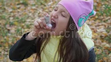 一个戴着帽子和夹克的女孩在秋林散步时以吸入剂的形式吃药治疗<strong>支气管哮喘</strong>。 流感